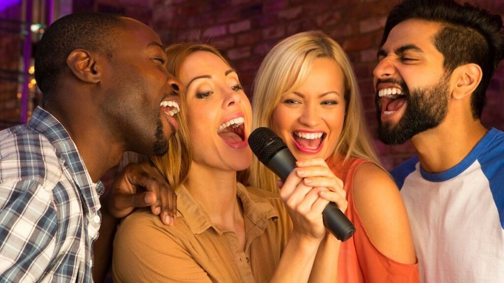 People gathered around a karaoke mic singing