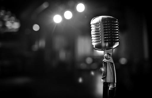 Black and white photo of an old style microphone and stage lights