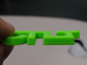 First Test Print - four connected letters for CTLT, and the print shows a bulging near the bottom of the print but is pretty good otherwise.