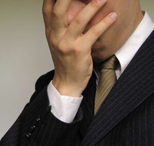 Man in suit, face buried in hand