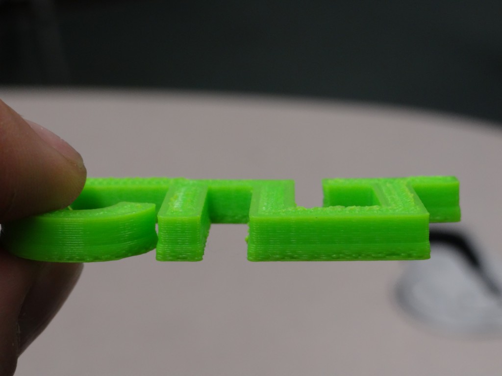 First Test Print - four connected letters for CTLT, and the print shows a bulging near the bottom of the print but is pretty good otherwise.